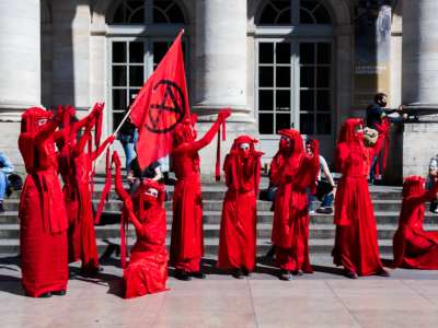 Climate protestors dressed in red stand on steps in Bordeaux, France