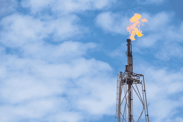 Gas flaring in front of some cloudy blue skies.