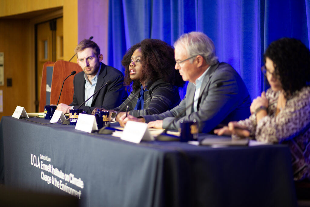 A lineup of four panelists sitting down close to microphones and deliberating.