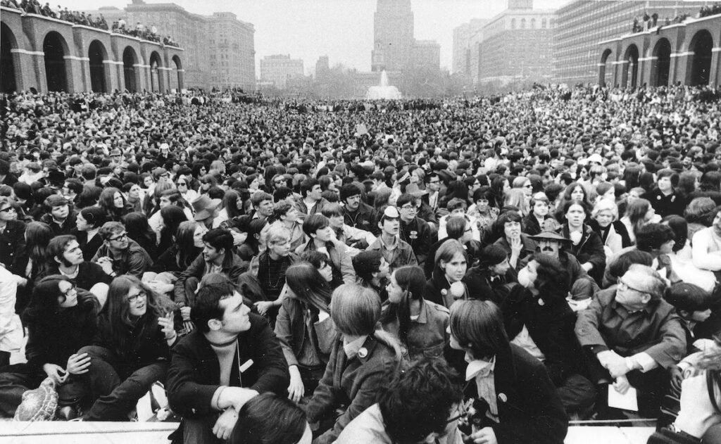 A black and white photo of thousands of students crowded into a university quad,