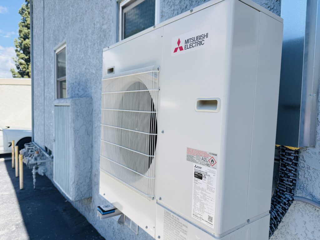 A close up of a Mitsubishi Electric heat pump on the exterior wall of a building.