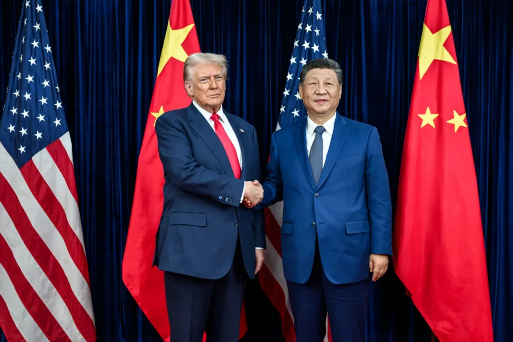 The presidents of the US and China standing on a stage and shaking hands with flags behind them