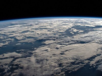 Earth seen from space, showing the planets curved horizon and cloud-covered surface against the black sky.